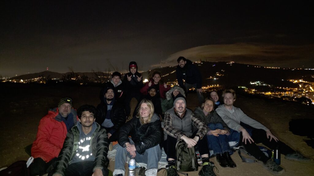 Group of people enjoying a night picnic while watching the Geminid meteor shower near Barcelona